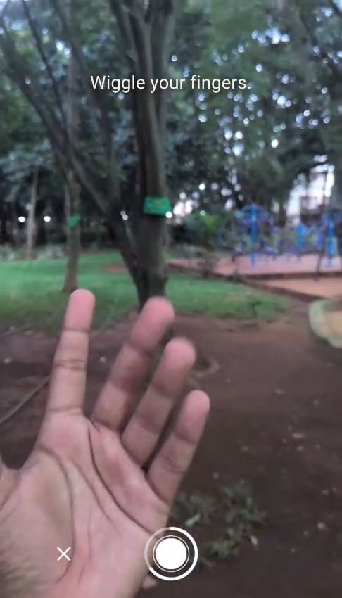 Camera view of a park with an open hand in frame and the prompt wiggle your fingers.